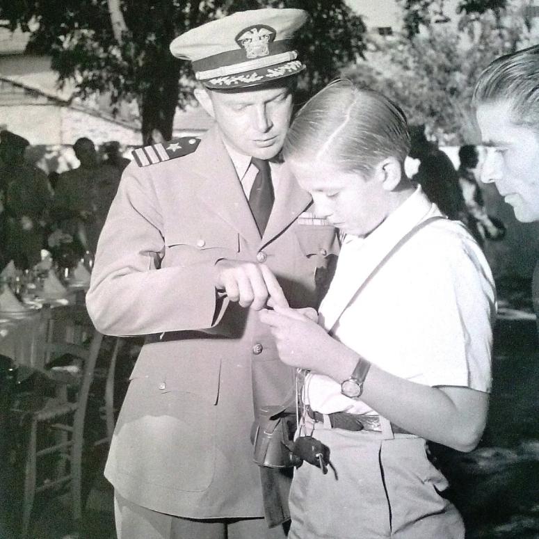 Cdr. Hudgins explains a Minox Camera to Crown Prince Constantine of Greece. 
